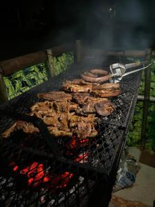 a bunch of meat cooking on a grill at Bush Adventure Guest House in Kasane