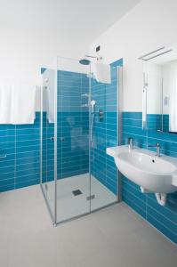 W łazience znajduje się umywalka i przeszklony prysznic. w obiekcie Hotel Villa Bernt w Grado