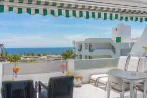 a balcony with chairs and tables and a view of the ocean at Lolas in Puerto del Carmen