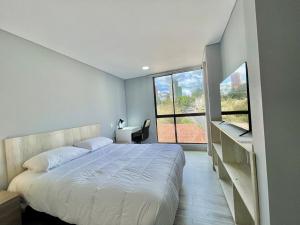 a bedroom with a bed and a desk and a window at New Cozy and Modern Gym Coworking Terrace in Bogotá +31 photos