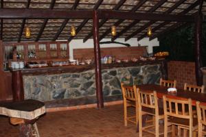 a restaurant with a bar with wooden tables and chairs at Pousada Moinho De Vento in Bonito