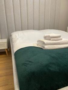 a bed with a green blanket and towels on it at Apartament Drugi Dom Sztutowo Baltic Twins in Sztutowo