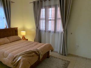 a bedroom with a bed and a window with curtains at The Cozy Retreat, Warm & Inviting in Kampala