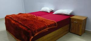 a bed with a red comforter and two pillows at Royal Suites kangarappady in Cochin