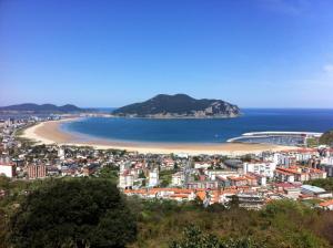 a view of a city and a beach with a mountain at El sol y la mar in Colindres