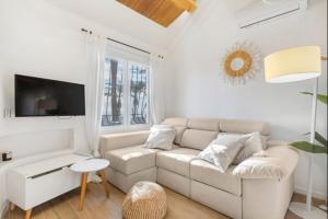 a white living room with a couch and a tv at Luxury on the beachfront in El Campello
