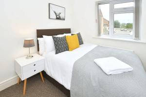 a white bedroom with a bed and a window at Kiln Side by Truestays - 3 Bedroom House in Etruria