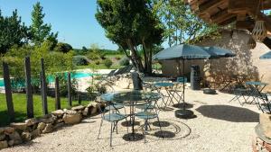a table with chairs and an umbrella next to a pool at Le puits de Jussens in Castelnau-de-Lévis