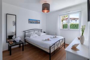 a white bedroom with a bed and a window at Appartement Iris - Welkeys in Ciboure