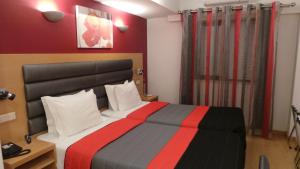 um quarto de hotel com uma cama com uma parede vermelha em Hotel Dom João Lisboa em Lisboa