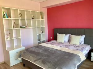 a bedroom with a bed and a red wall at Sunny Lotus Apartamentai in Druskininkai
