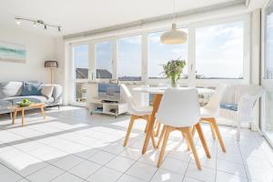 a living room with a table and white chairs at Meerkieker in Albertsdorf +34 photos