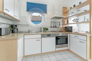 a kitchen with white cabinets and a window at Meerkieker in Albertsdorf