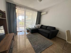 - un salon avec un canapé noir et une grande fenêtre dans l'établissement Apartment in the complex Olymp, à Sveti Vlas 3 autres photos