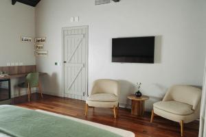 a bedroom with two chairs and a flat screen tv at Casa Toledo in La Cumbre
