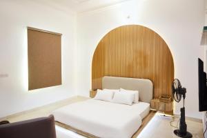 ein Schlafzimmer mit einem weißen Bett mit einem hölzernen Kopfteil in der Unterkunft Tee-whyte private home in Gwarinpa
