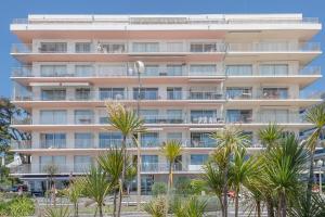 a tall building with palm trees in front of it at Vue sur mer La Baule Victoria in La Baule
