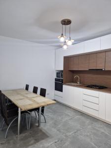 a kitchen with a wooden table and a kitchen with white cabinets at Villa Niko in Mamaia Sat/Năvodari