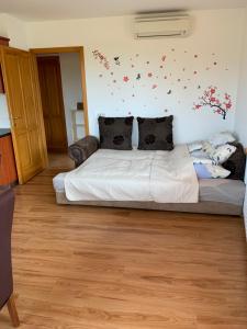 a bedroom with a white bed with butterflies on the wall at Hunor Apartmanok Napsugár in Balatonlelle