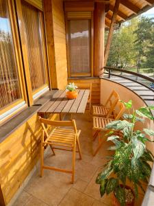 a porch with a wooden table and chairs on it at Hunor Apartmanok Napsugár in Balatonlelle +1 photo