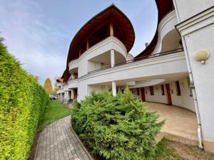 a large white building with a tree in front of it at Hunor Apartmanok Napsugár in Balatonlelle