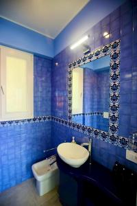 a blue tiled bathroom with a sink and a mirror at Casa Damico in Castelmola +34 photos