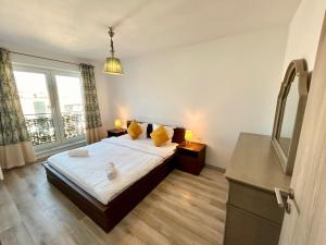 a bedroom with a bed with yellow pillows and a window at JAD Luxury Apartments Kasper in Braşov