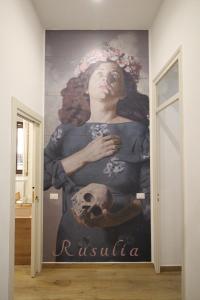 un murale di una donna che tiene in mano un teschio su un muro di Leoni di Sicilia a Palermo