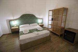 una camera da letto con un letto grande con testiera verde di Leoni di Sicilia a Palermo