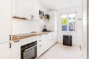 a white kitchen with white cabinets and a window at La Pause - Maison de charme avec terrasse - 2 chambres in Dinard +12 photos
