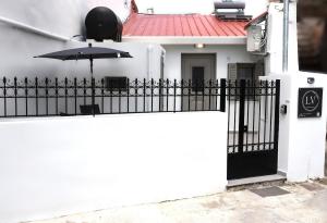 a white house with a black gate and an umbrella at LV Home Lasithi in Agios Georgios
