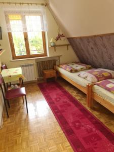 a bedroom with two beds and a table and window at Willa Pod Brzozami in Korbielów