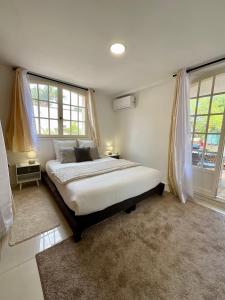 a bedroom with a large bed and two windows at Appartement avec piscine et barbecue in La Farlède