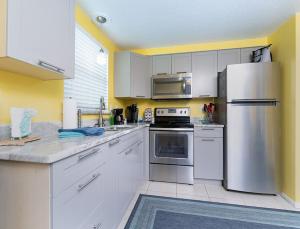 a kitchen with white cabinets and a stainless steel refrigerator at Turtle Cay in Englewood