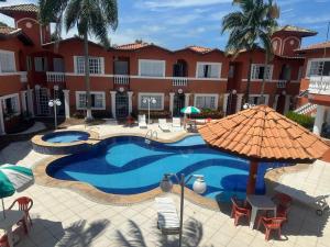 a resort pool with chairs and an umbrella at Villaggio Boccia in Bertioga