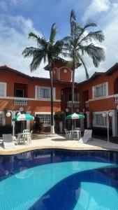 a swimming pool in front of a building with palm trees at Villaggio Boccia in Bertioga +1 photo