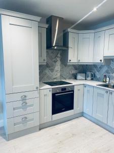 レタケニーにあるStarlight Apartments, Suite 6, Letterkenny Townの白いキャビネットとコンロ付きオーブンを備えたキッチン
