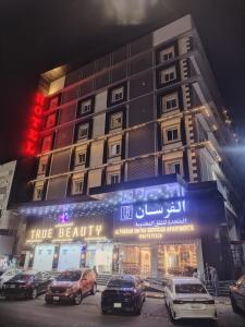 Un edificio con coches aparcados delante. en شقق الفرسان حى الفيصلية اماسي البشاير, en Yeda