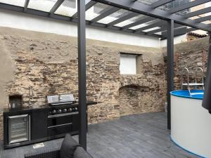 an outdoor kitchen with a stone wall and a stove at 1-Zimmer-Apartment mit Pool in Ellenz-Poltersdorf