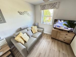 a living room with a couch and a flat screen tv at Dudleys Retreat - Part of the The Bay Filey Holiday Village with pool, gym and direct beach access, pub, restaurant, tennis and meadows walks in Filey