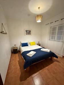 a bedroom with a large bed with a blue blanket at Refúgio das Alfazemas in Vila Nova de Milfontes