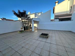 a patio with a tree and a white wall at Refúgio das Alfazemas in Vila Nova de Milfontes