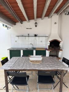 a kitchen with a table with chairs and a sink at Refúgio das Alfazemas in Vila Nova de Milfontes
