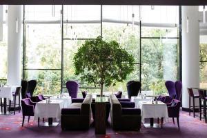 a dining room with tables and chairs and a plant at Radisson Blu Hotel, Montpellier in Montpellier