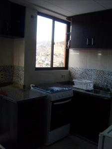 Il comprend une cuisine équipée d'une cuisinière. four supérieur à côté d'une fenêtre dans l'établissement A Place in the Sky - c23 Calacoto, à La Paz