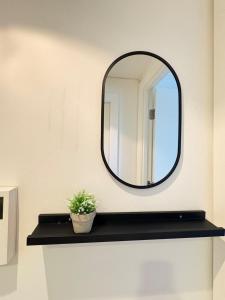 a mirror on a wall with a plant on a shelf at Cosy Flat Leeds City Centre in Central Station +36 photos