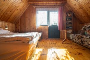 a bedroom with a bed and a window and wooden walls at Domek nad jeziorem in Kretowiny