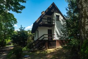 a small white house with a black roof at Domek nad jeziorem in Kretowiny