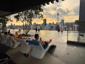 een groep mensen die op stoelen op een zwembad op het dak zitten bij Residence Axon Apartment Bukit Bintang by TaheeenS in Kuala Lumpur