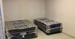Senador CanedoにあるEspaço Venezaの部屋にはプラスチックのカバーがかけられたベッドが2つある